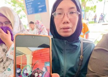 ZAHARAH Hamzah menunjukkan gambar kenangan bersama anaknya, Nur Khairiah Mat Mazlin ketika beraya bersama keluarga di Endau, Mersing, tahun lalu. - UTUSAN/AMRAN ALI