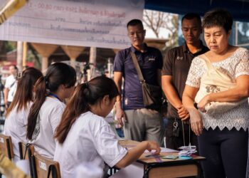 SEORANG wanita mendaftar di sebuah pusat pengundian di Bangkok, hari ini. - Foto AFP