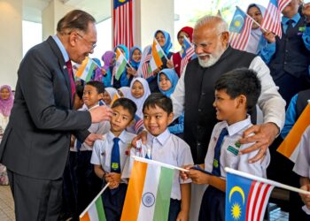 ANWAR Ibrahim bersama Perdana Menteri India, Narendra Modi menyantuni pelajar sekolah yang mengibarkan bendera kedua-dua negara pada Majlis Sambutan Rasmi Perdana Menteri India di Kompleks Seri Perdana, Putrajaya, semalam. – PEJABAT PERDANA MENTERI