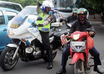 GAMBAR fail anggota polis bercakap dengan penunggang motosikal di Jakarta. - Foto AFP
