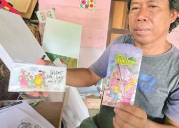 MUHAMMAD Najid Mohd. Rudin menunjukkan kad dan sampul duit raya dihasilkan di bengkelnya di Kampung Parit 3, Hutan Melintang, Bagan Datuk. – MINGGUAN/AIN SAFRE BIDIN