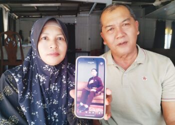 ROSDE Yaakub (kiri) dan Juariah Ab. Rahman menunjukkan gambar Allahyarham Muhammad Mustaqim Rosde memakai baju Melayu pilihannya pada 2025 di Kampung Telaga Nibong, Besut, Terengganu. – UTUSAN/WAN ZURATIKAH IFFAH WAN ZULKIFLI