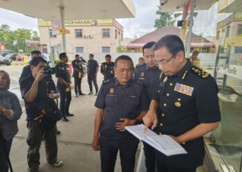 AZMAN Adam (kanan) bersama pegawai semasa melakukan pemeriksaan buku log disebuah stesen minyak berhampiran sempadan Malaysia-Thailand, Rantau Panjang, Kelantan hari ini-UTUSAN/YATIMIN ABDULLAH.