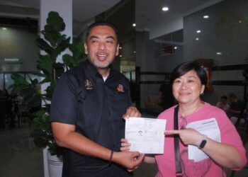 MOHD. Noor Helmy Abdul Halem bersama Lee Kim Choo menunjukkan permohonan pertukaran alamatnya Program Hari Ahli Majlis MMKN bersama Rakyat (HEBAT) Siri 1 Tahun 2026 di Seri Negeri, Melaka, semalam. - UTUSAN/AMRAN MULUP