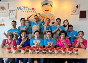 YEOH Li Mei (duduk, dua kiri) bergambar bersama sukarelawan dan lapan lelaki OKU yang menghasilkan biskut untuk dijual sempena sambutan Tahun Baharu Cina di PEKAKA Workshop di Taman Intan, Sungai Petani, Kedah.