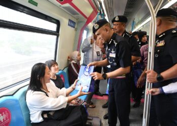 SHAZELI Kahar memberikan cenderamata kepada para penumpang MRT pada Walkabout Langkah Selamat Santuni Komuniti Kajang di Stesen MRT Kajang, Selangor hari ini.-UTUSAN/FARIZ RUSADIO