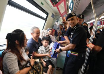 SHAZELI Kahar memberikan cenderamata kepada para penumpang MRT pada Walkabout Langkah Selamat Santuni Komuniti Kajang di Stesen MRT Kajang, Selangor hari ini.-UTUSAN/FARIZ RUSADIO