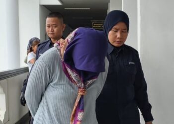 TERTUDUH diiringi anggota polis selepas dijatuhi hukuman denda oleh Mahkamah Majistret Ayer Keroh hari ini selepas mengaku terlibat aktiviti persundalan. - UTUSAN/AMRAN ALI