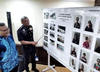 ALZAFNY Ahmad (kanan) menunjukkan gambar-gambar sekitar Op Hazard E-Waste sambil diperhatikan Abdul Aziz di Ibu Pejabat Polis Kontinjen (IPK) negeri, Seremban, hari ini. -  UTUSAN/MOHD. SHAHJEHAN MAAMIN
