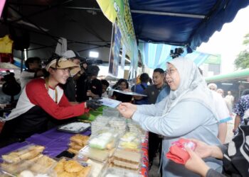 FUZIAH Salleh menyampaikan kad diskaun khas kepada seorang peniaga pada Majlis Pelancaran Bazar Ramadan Rahmah Madani Peringkat Kebangsaan dan I - FB@BRR 2026 di Taman Perling, Johor Bahru, semalam.-UTUSAN/RAJA JAAFAR ALI