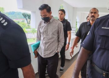 FAHMI Zainol (tengah) diiringi anggota polis ketika hadir di Mahkamah Balik Pulau, Pulau Pinang atas pertuduhan dengan sengaja mencederakan isterinya dalam satu kejadian pada 22 Februari lalu.-UTUSAN/DANIAL SAAD