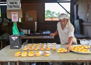 WAN Jusoh Wan Ngah menyusun kuih akok tradisional yang dijual di gerai pandu beli tanpa penjual di Kampung Baru Serada, Kuala Terengganu, Terengganu. – UTUSAN/PUQTRA HAIRRY