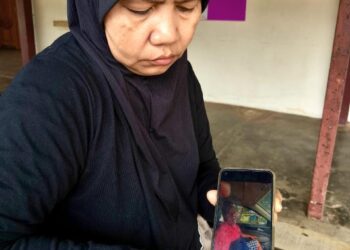 ANISAH Ibrahim menunjukkan gambar Fakrurozi Yusof yang maut akibat serangan jantung selepas terlibat kemalangan ketika di Besut, Terengganu. - UTUSAN / WAN ZURATIKAH IFFAH WAN ZULKIFLI