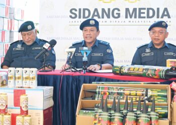 ROSLAN  Yusoff (tengah) bersama sebahagian mercun dan bunga api yang dirampas dalam operasi yang dijalankan oleh Jabatan Kastam Diraja Malaysia (JKDM) Melaka. – UTUSAN/AMRAN ALI