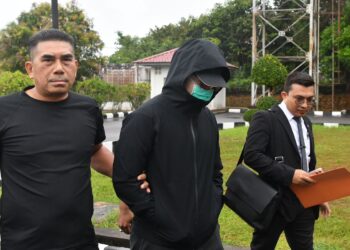 TERTUDUH (tengah) semasa dibawa untuk prosiding perbicaraan di Mahkamah Kuala Krai, Kelantan.- UTUSAN/ROSMIZAN RESDI