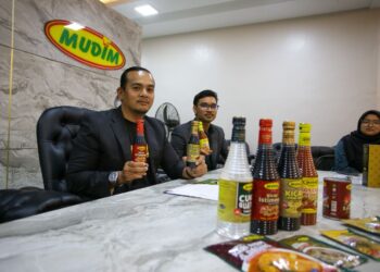 MOHD. Izzad Al Syafiq Abdul Karim (kiri) menunjukkan produk keluaran Mudim Zakaria Food Industries ketika ditemui pemberita di kilang syarikat itu di Kampung Jelutong, Pendang, Kedah, semalam. - UTUSAN/SHAHIR NOORDIN