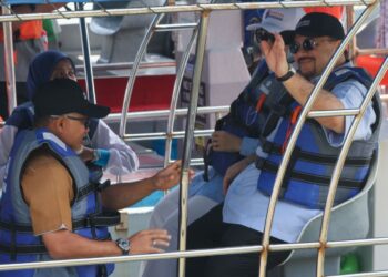 AMIR Hamzah Azizan (kanan) melambai tangan ketika menaiki bot untuk meninjau sekitar Sungai Betong dan pesisir Pantai Pasir Panjang semasa sesi turun padang di Kampung Angkat Madani Pulau Betong, Balik Pulau, Pulau Pinang hari ini. - UTUSAN/DANIAL SAAD