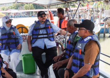 AMIR Hamzah Azizan menaiki bot untuk meninjau keadaan sekitar Sungai Betong dan pesisir Pantai Pasir Panjang ketika sesi turun padang di Kampung Angkat Madani Pulau Betong di Balik Pulau, Pulau Pinang hari ini. - UTUSAN/DANIAL SAAD