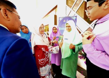 SEORANG guru mengimbas aplikasi StudentQR pada baju seorang pelajar selepas Majlis Pelancaran Program Adat dan Identiti Murid Pahang: Aplikasi StudentQR di Kuantan, Pahang. - UTUSAN/SHAIKH AHMAD RAZIF