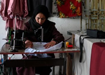 RAHIMA sedang menyulam selendang dan pakaian di buktiknya di Bamiyan. 
– AFP