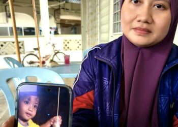 NUR Liah Asul menunjukkan gambar arwah anaknya yang disimpan ketika ditemui dekat Kampung Seri Cheeding, Banting, Kuala Langat, Selangor. - UTUSAN/MOHD. FARHAN DARWIS