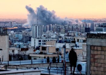 SEORANG individu berdiri di atas bumbung sebuah bangunan melihat kepulan asap selepas serangan ke atas ibu negara Iran, Teheran, Selasa lalu.