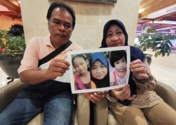 SITI Aishah Ariffin (kanan) dan Rusdi Rani menunjukan gambar kenangan tiga anaknya yang dibunuh 13 tahun lalu ketika ditemui di Kuala Terengganu, Terengganu.