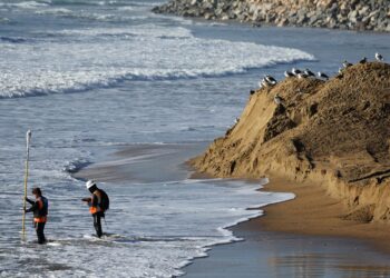 PEKERJA mengukur ketinggian pasir di sepanjang garis pantai yang terhakis di San Clemente, California. - AFP
