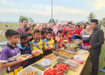 MOHD. Faizie Shuib mengagihkan juadah kepada murid-murid daripada pelbagai kaum bersempena Majlis Iftar Perpaduan Madani di padang SK Dato’ Ahmad Musa, Kangar, Perlis.