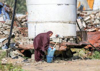 SEORANG wanita mengambil air daripada sebuah tangki di khemah pelarian Bureij di tengah Gaza, kelmarin. –  AFP