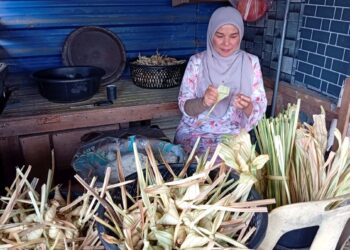 FARIDAH Mamat menganyam dan membungkus ketupat daun palas di gerainya di Kampung Manir, Kuala Terengganu. – UTUSAN/ERMA YUSNIDA JUSOH