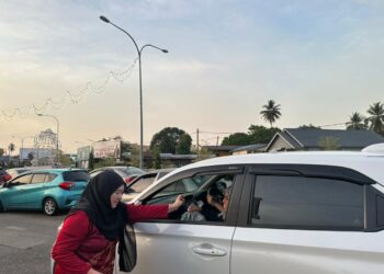 CHE Norhayati Mohamed (kiri) mengagihkan juadah berbuka kepada perantau di laluan Gua Musang-Kuala Krai, Kelantan.