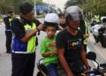 MOHD. Zamri Samion (kiri) memakaikan topi keledar baharu kepada pembonceng motosikal pada Majlis Penutup Op HRA dan Operasi Khas Motosikal peringkat negeri di Jalan Sultan Mohamad, Kuala Terengganu, Terengganu. -UTUSAN/PUQTRA HAIRRY