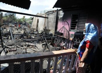 SITI Rozana Ibrahim sayu melihat rumahnya yang musnah dalam kebakaran melibatkan dua lagi buah rumah di Kampung Plentong Baru, Johor Bahru, semalam. UTUSAN/RAJA JAAFAR ALI