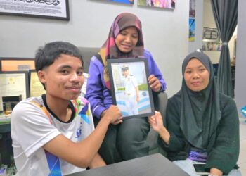 NOOR Ain Mohd. Ariffin (tengah)  bersama anak-anaknya melihat gambar Allahyarham Mohd. Shahrizan Mohd. Termizi ketika ditemui 
di Lekir, Sitiawan, Manjung. – UTUSAN/AIN SAFRE BIDIN