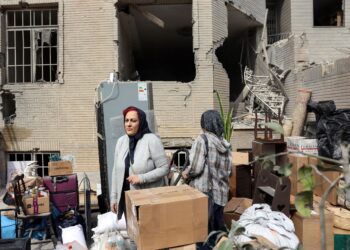 DUA wanita Iran mengambil barangan mereka dari sebuah bangunan kediaman yang rosak di Teheran, kelmarin.- AFP