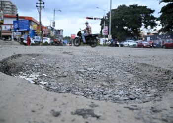 LUBANG besar di kawasan sebatang  jalan raya di India.- AFP
