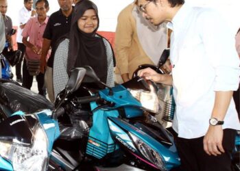 MUHAMMAD Kamil Abdul Munim menyerahkan motosikal kepada Nur Aisyah Mohd Nazri pada program di Ipoh semalam. - UTUSAN/LIYANA RAMLI