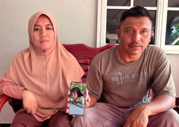 MOHD. Azlan  Abdul  Wahid dan isteri, Salina Saidun menunjukkan gambar Nur Annisa Husna ketika ditemui di  Kampung Simpang Empat  Pematang Pelandok di Teluk Intan semalam. – UTUSAN/AIN SAFRE BIDIN