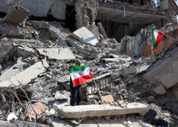 SEORANG lelaki mengibarkan bendera Iran di sebalik runtuhan bangunan kesan serangan udara oleh Amerika Syarikat (AS) dan sekutunya ke atas Teheran, kelmarin. Serangan terhadap Iran sudah memasuki hari keenam dengan kira-kira 1,000 orang dilaporkan terbunuh. – AFP