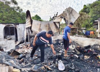 MUHAMAD Azrizal Abad (kiri) dan abangnya, Muhamad Asyraf  melihat keadaan rumah mereka yang musnah dalam kebakaran di Kampung Kepayang, Ipoh semalam.