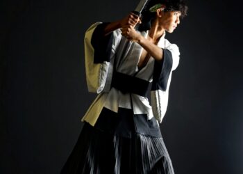 Muhammad Uzair Md. Roslan menempatkan dua sumber cahaya berpusat untuk memberikan kesan simetri kepada ruang wajah, tangan dan hulu pedang, sambil membiarkan sebahagian besar subjek dan latar belakang tenggelam dalam kegelapan pekat.