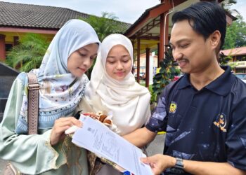 WAN Aleya Batrisyia Meor Ruslan (tengah) meraih 9A dalam peperiksaan SPM 2025 menunjukkan slip keputusan kepada ibu bapanya di SMK Raja Permaisuri Bainun, Ipoh hari ini.