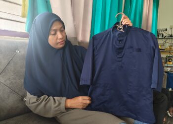 SITI Hajar Ismail melihat baju Melayu yang sering dipakai Allahyarham Muhamad Zarif Mohd. Hazahari ketika dia ditemui Utusan Malaysia di rumahnya di Kampung Batu Rakit, Kuala Nerus, Terengganu. 
– UTUSAN/ ERMA YUSNIDA JUSOH