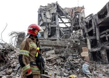 Seorang anggota bomba berdiri di hadapan runtuhan sebuah bangunan kediaman di Teheran pada Khamis lalu. - AFP