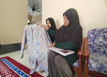 NORINDA Kasim (kanan) menunjukkan baju kurung Nur Dalila Farhana Mohamad Isma ketika ditemui 
di Kampung Baru Tok Dor, Besut, Terengganu.