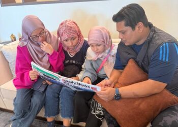 NORHANI Aida Mohd. Nor (kiri) bersama dua anaknya membaca berita di akhbar tentang situasi terkini serangan ketika mendapat perlindungan di sebuah hotel di Juffair, Bahrain.