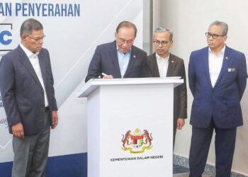 ANWAR Ibrahim menandatangani plak perasmian Pusat Respons Penipuan Kebangsaan (NSRC) di Menara 2, MCMC di Cyberjaya, semalam.