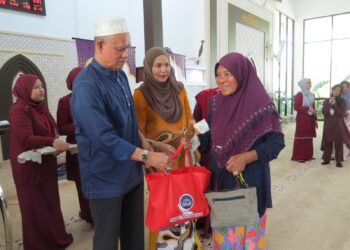 CHE Ibrahim Che Ismail (kiri) menyampaikan sumbangan wang zakat kepada Mek Esah Hamad di Masjid Mutiara Hentian Gua Musang di Tanah Putih, Gua Musang, Kelantan.