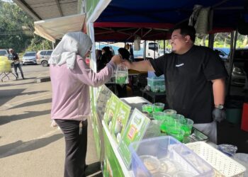 HASBULLAH Baharuddin menghulurkan pisang ijo kepada pelanggannya di Bazar Ramadan Bataras, Tawau, Sabah.